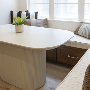 Detail of fluted pedestal table beside chevron-textured banquette cushions and quartz counter edge