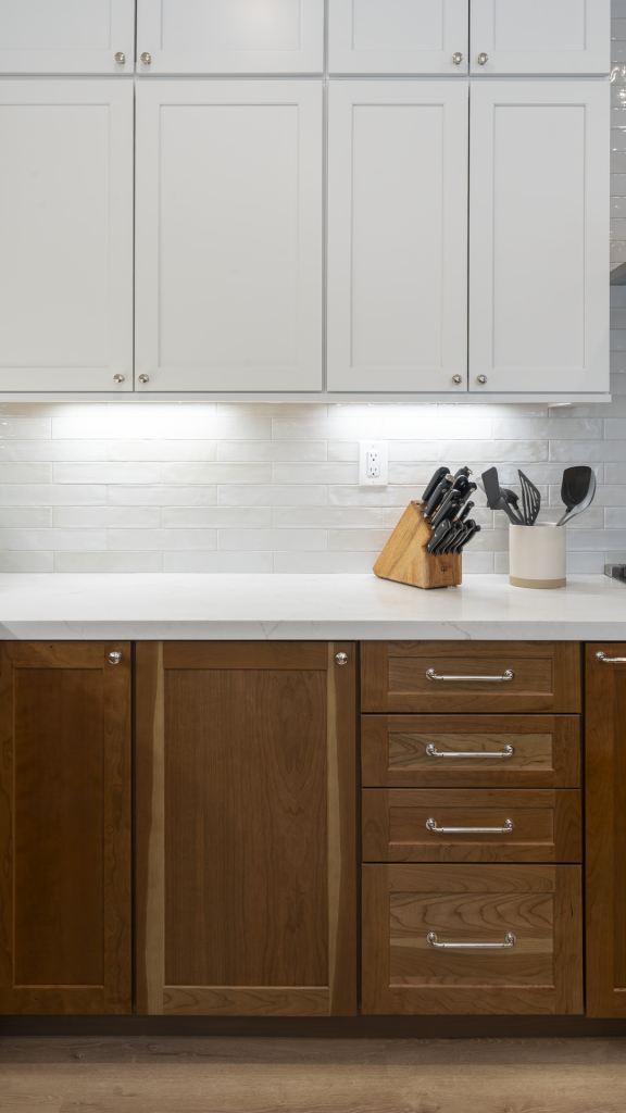 Detail of walnut base drawers with chrome pulls, white subway backsplash, and quartz countertop
