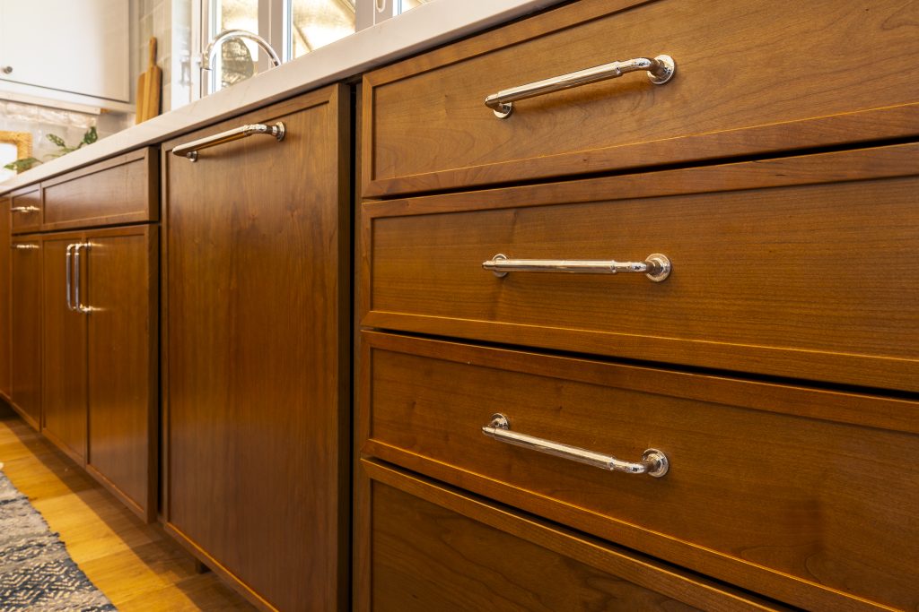 Close-up of polished bar pulls on Cherry Amber drawers below quartz counters
