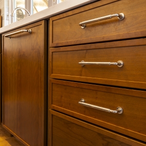 Close-up of polished bar pulls on Cherry Amber drawers below quartz counters