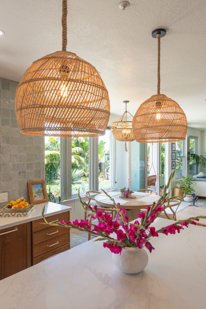 Woven dome pendants over quartz island with bright pink florals, dining nook, and floor-to-ceiling windows