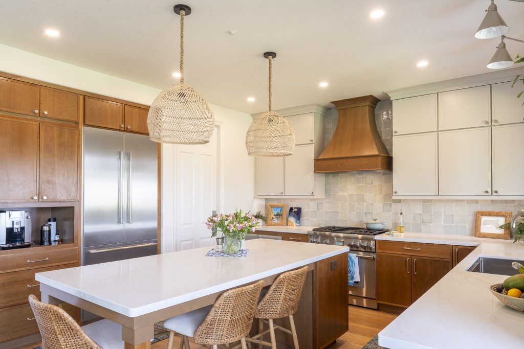 Island seating with woven stools and pendants facing custom wood hood and two-tone cabinetry