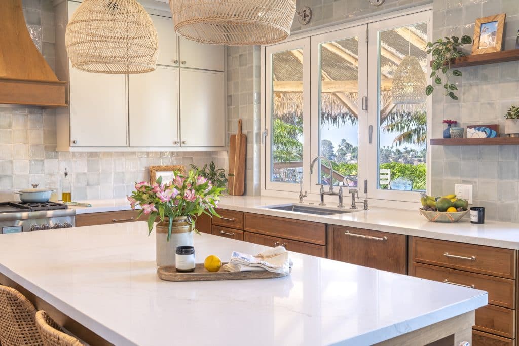 Quartz island vignette looking to sink wall—woven pendants, Painted Harbor uppers, Cherry Amber lowers, and full-height ceramic backsplash