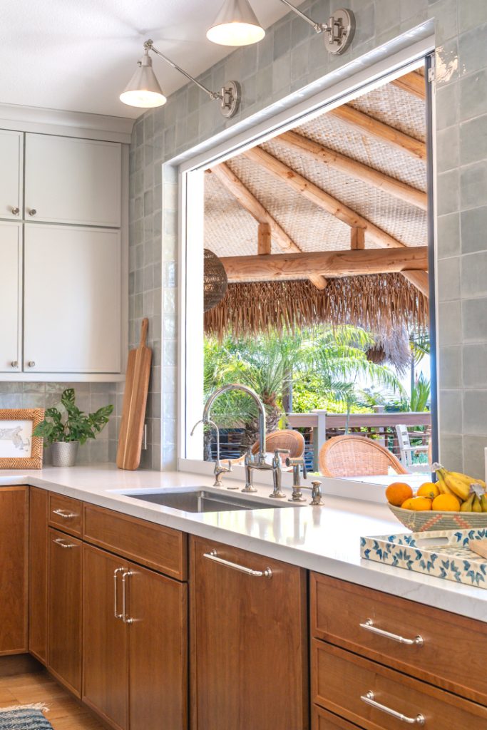 Sink corner with Kohler Edalyn bridge faucet, enlarged window, trio of sconces, Marin tile, and Cherry Amber bases