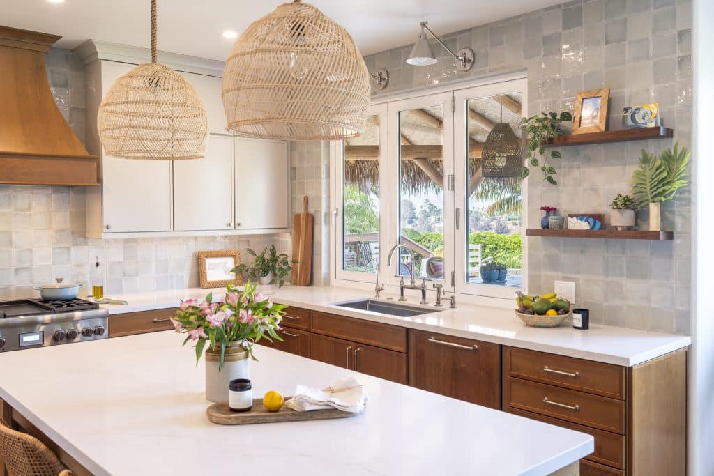 Expanded kitchen window with three sconces over Rohl undermount sink and Kohler Edalyn bridge faucet, open walnut shelves, and Marin tile