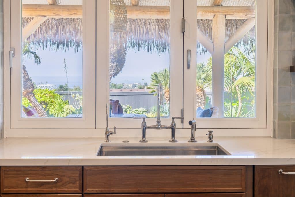 Enlarged kitchen window over Rohl undermount sink with Kohler Edalyn bridge faucet and quartz counters