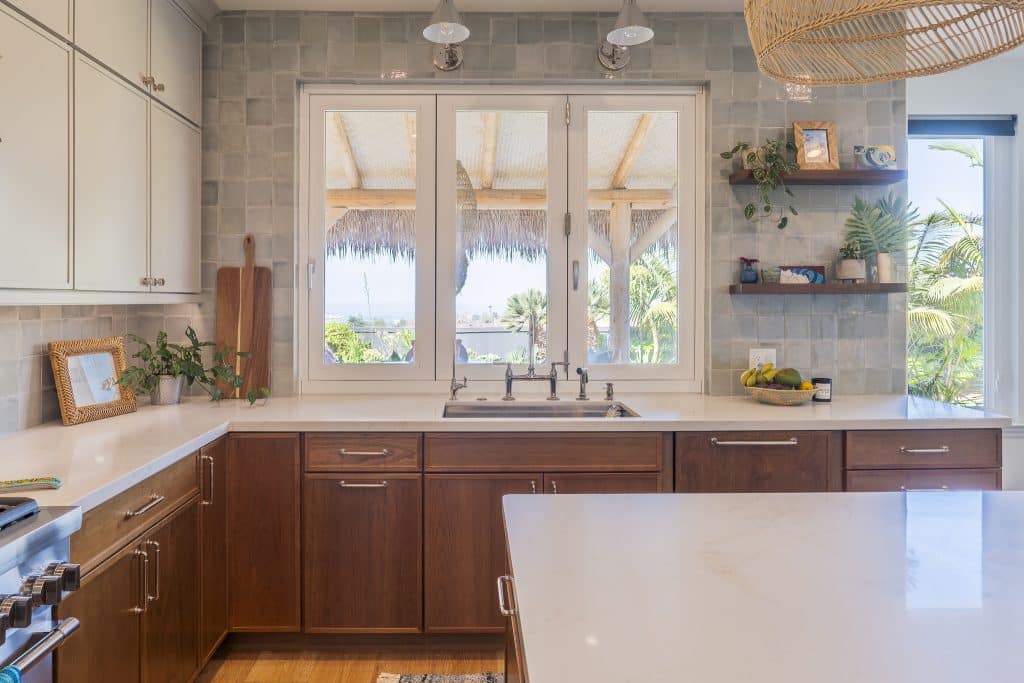 Close view of enlarged kitchen window and bridge faucet with open display shelves and drawer bases in Cherry Amber