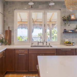 Close view of enlarged kitchen window and bridge faucet with open display shelves and drawer bases in Cherry Amber