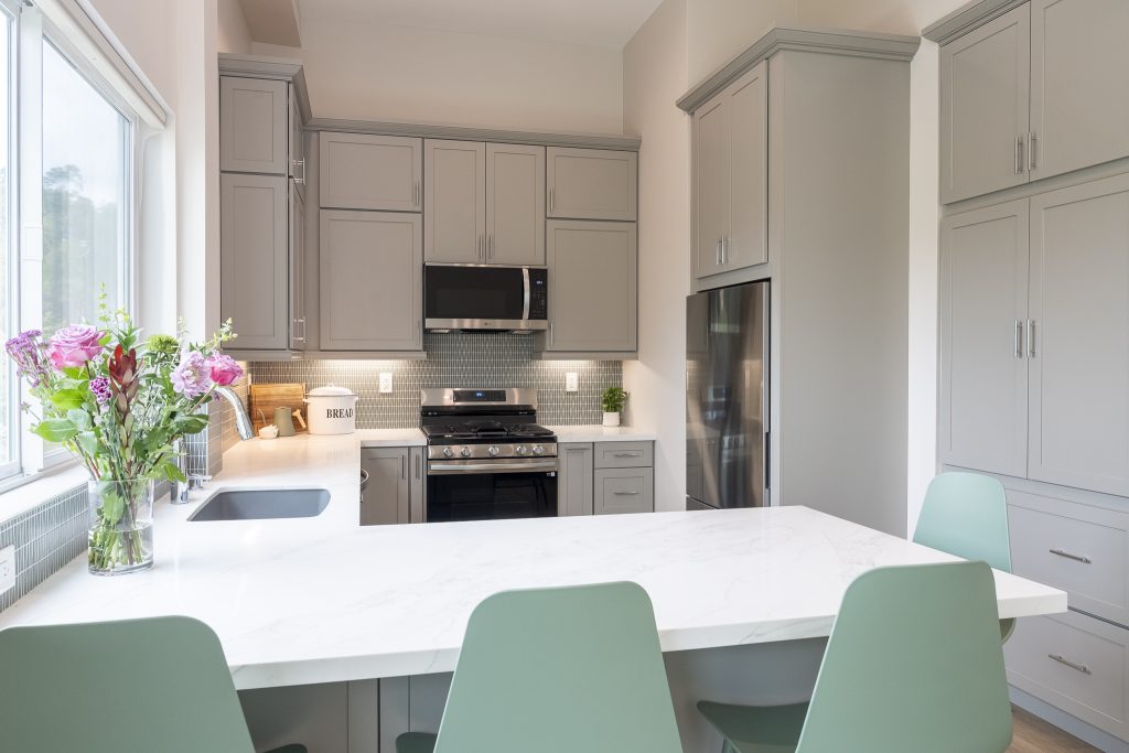Quartz peninsula with flowers and soft-gray cabinetry