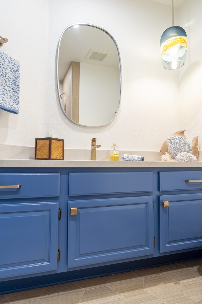 Oval mirror with coastal glass pendant above the vanity