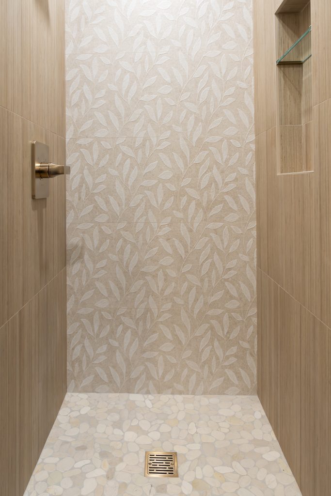 Pebble shower floor meeting a leaf-pattern feature wall in the downstairs bath