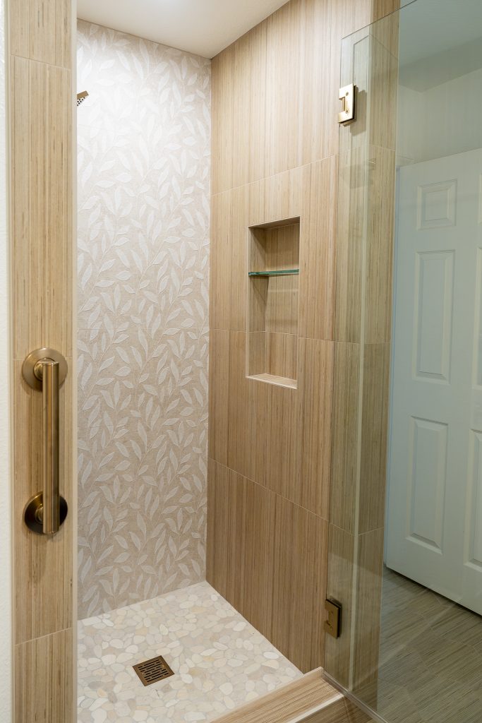 Shibusa porcelain shower with pebble mosaic floor and brass grab bar