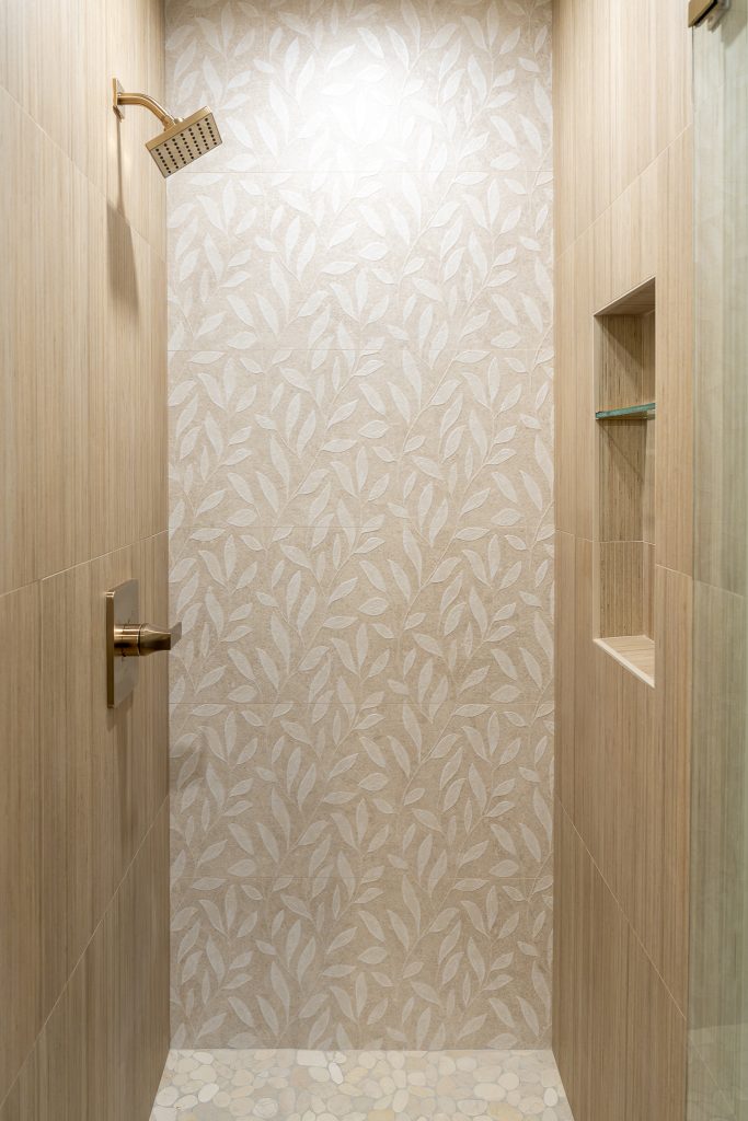 Leaf-pattern Wynwood feature wall with brass shower trim and built-in niche