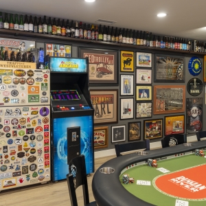Arcade cabinet and stickered fridge along gallery wall