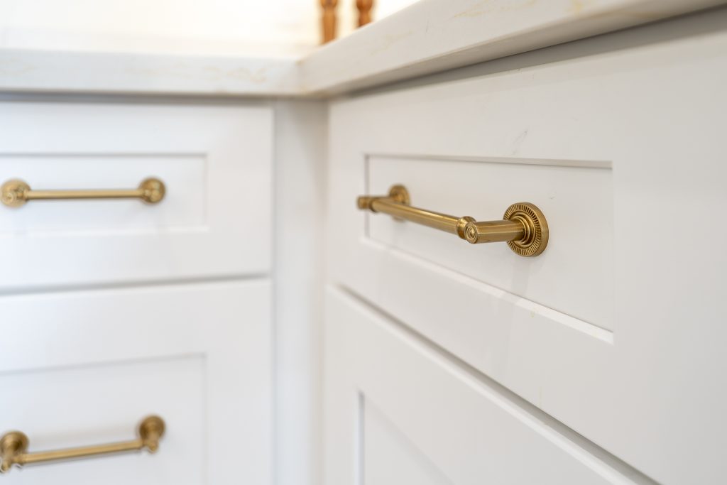 Brass drawer pulls detail on white Shaker base cabinets