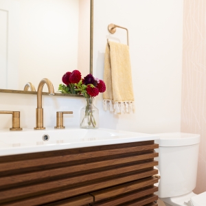 Powder bath vanity with brass faucet and soft patterned wallpaper