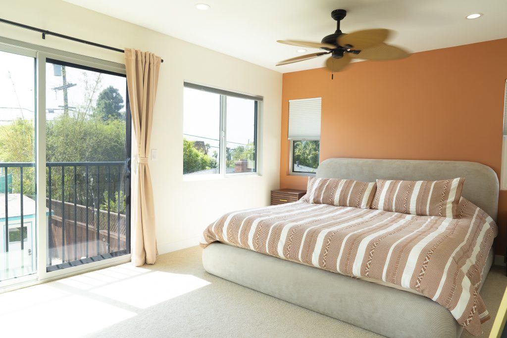 Primary bedroom with balcony slider and terracotta accent wall