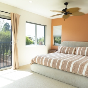 Primary bedroom with balcony slider and terracotta accent wall