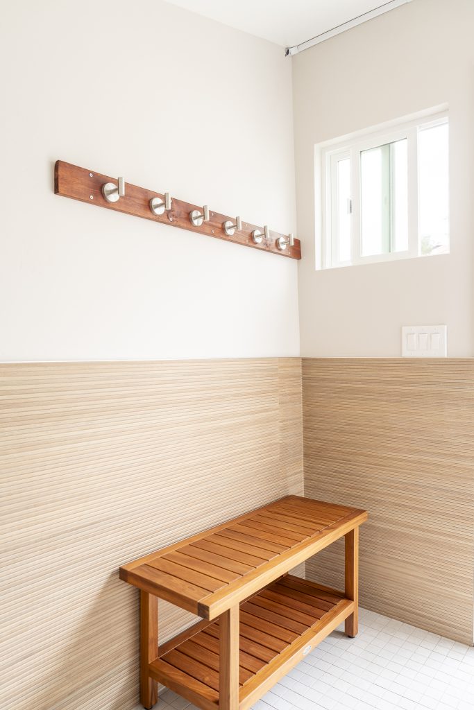 Wood bench and robe hooks over Porcelanosa wainscot