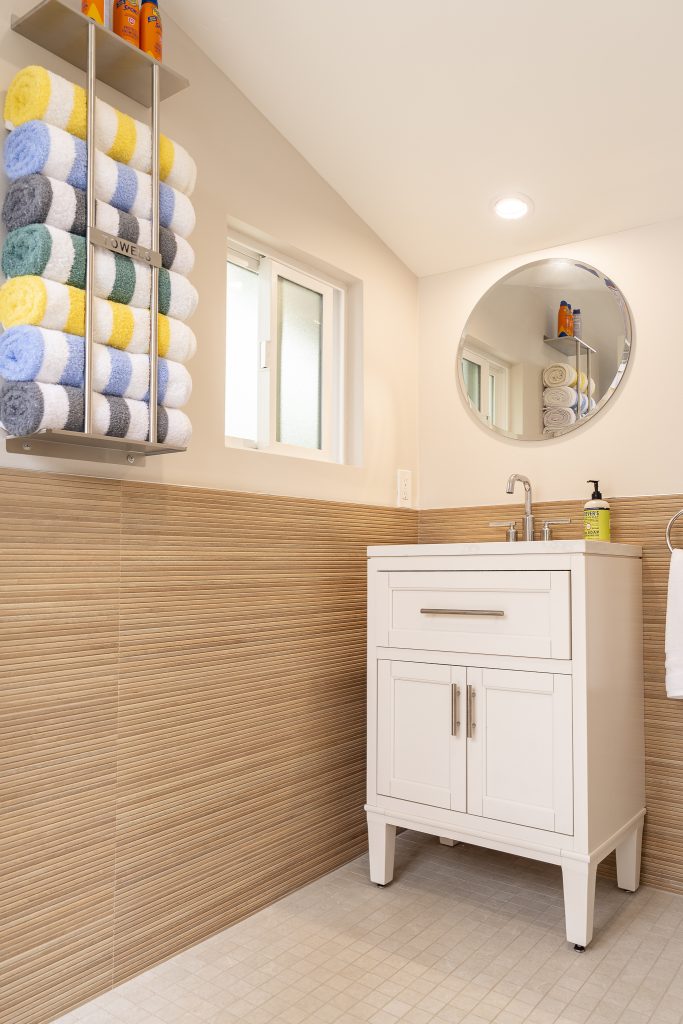 Pool bath vanity with round mirror and striped wainscot