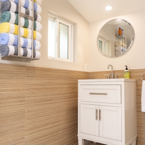 Pool bath vanity with round mirror and striped wainscot