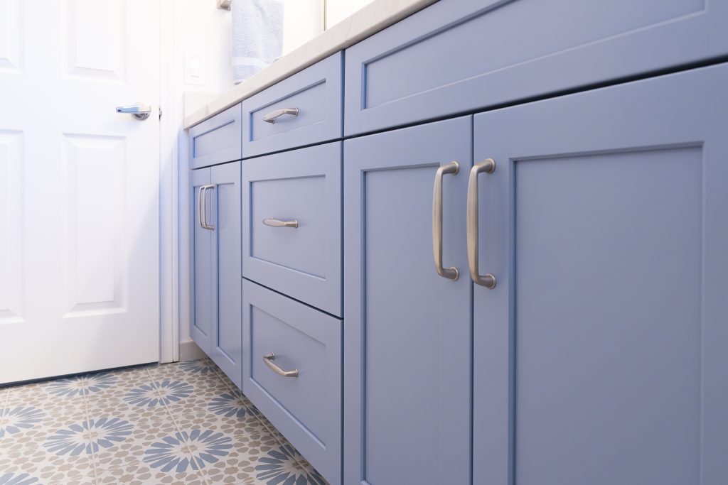 Low angle of blue vanity with Amerock Kane pulls over Ethnic patterned floor tile