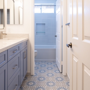 Patterned Ethnic porcelain floor with blue vanity leading to a Kohler Archer tub surround