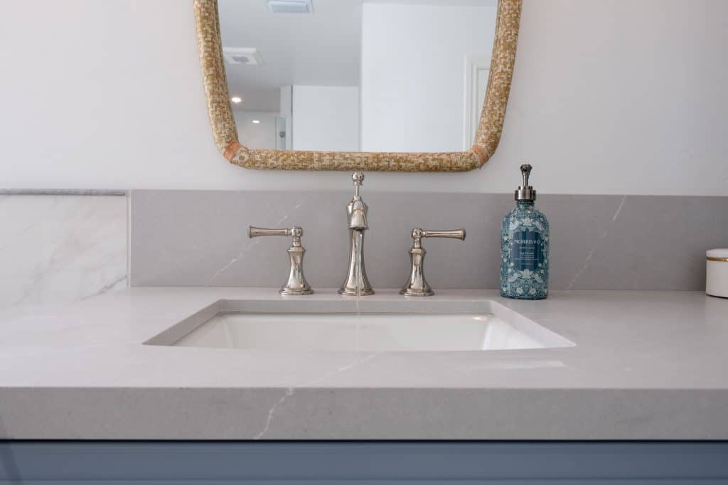 Undermount sink with chrome widespread faucet and quartz countertop detail