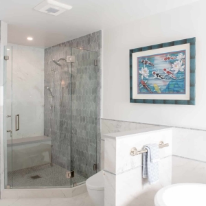 Glass-enclosed walk-in shower with blue-gray accent tile and marble-look wall tile