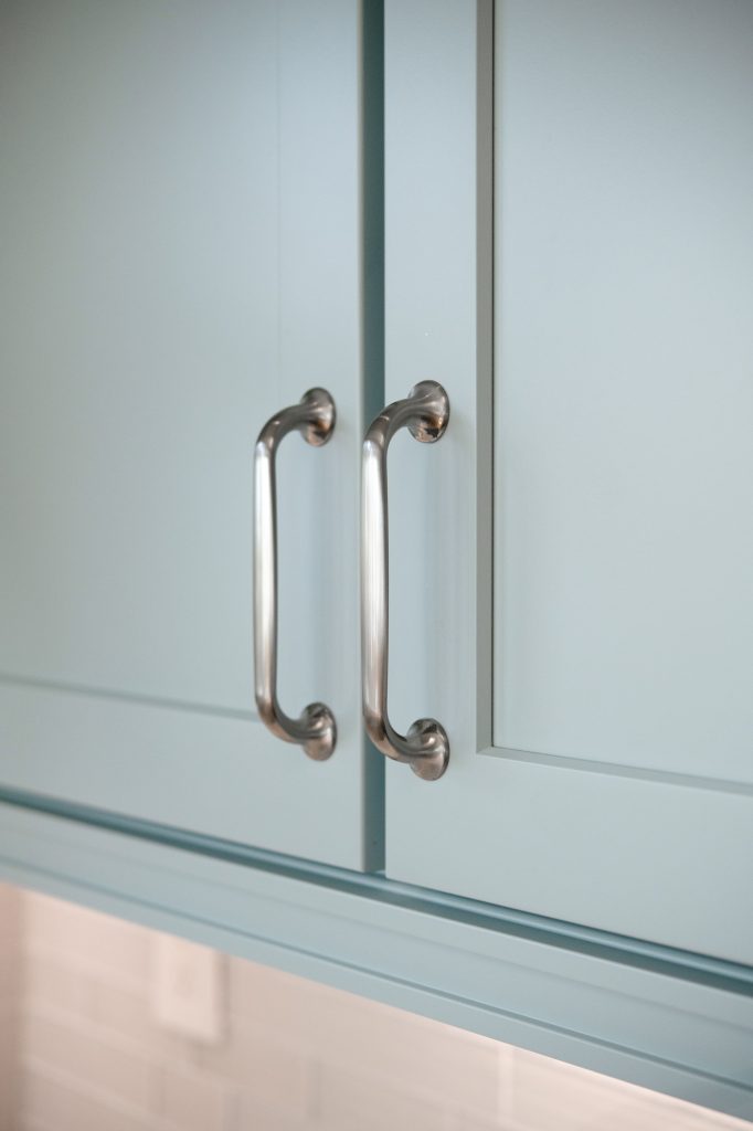 Close-up of Top Knobs Oculus cabinet pulls on custom blue shaker cabinet doors