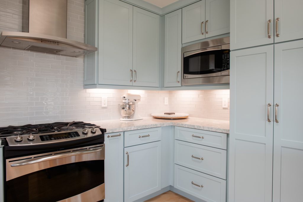 Tall pantry cabinetry and built-in microwave with blue cabinet finish and quartz countertop