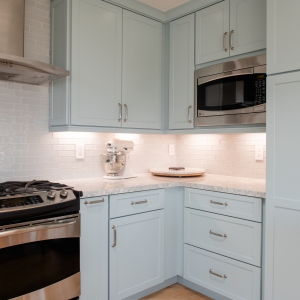Tall pantry cabinetry and built-in microwave with blue cabinet finish and quartz countertop