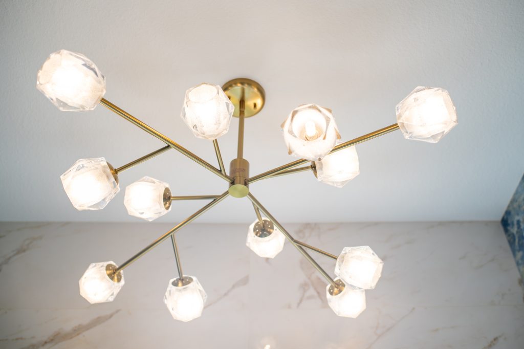 Close-up of a brass chandelier with faceted glass shades in a bright bathroom