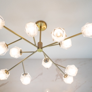 Close-up of a brass chandelier with faceted glass shades in a bright bathroom