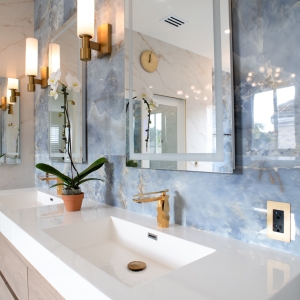 Double vanity with backlit mirrors, brass sconces, and a blue onyx-look tile feature wall