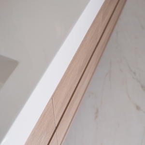 Close-up detail of a floating light-oak vanity with clean modern drawer lines