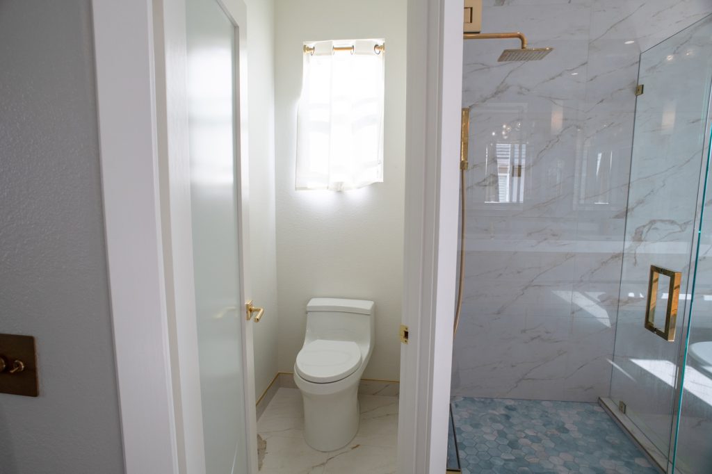 Blue hex mosaic shower floor with a brass curb edge beside a glass panel