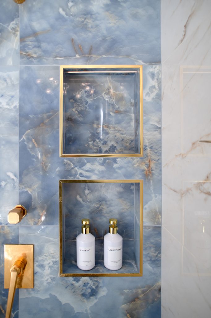 Custom shower niches in blue onyx-look tile with brass trim accents