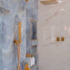 Luxury shower system with brass rain head, handheld wand, and valve trim on blue tile