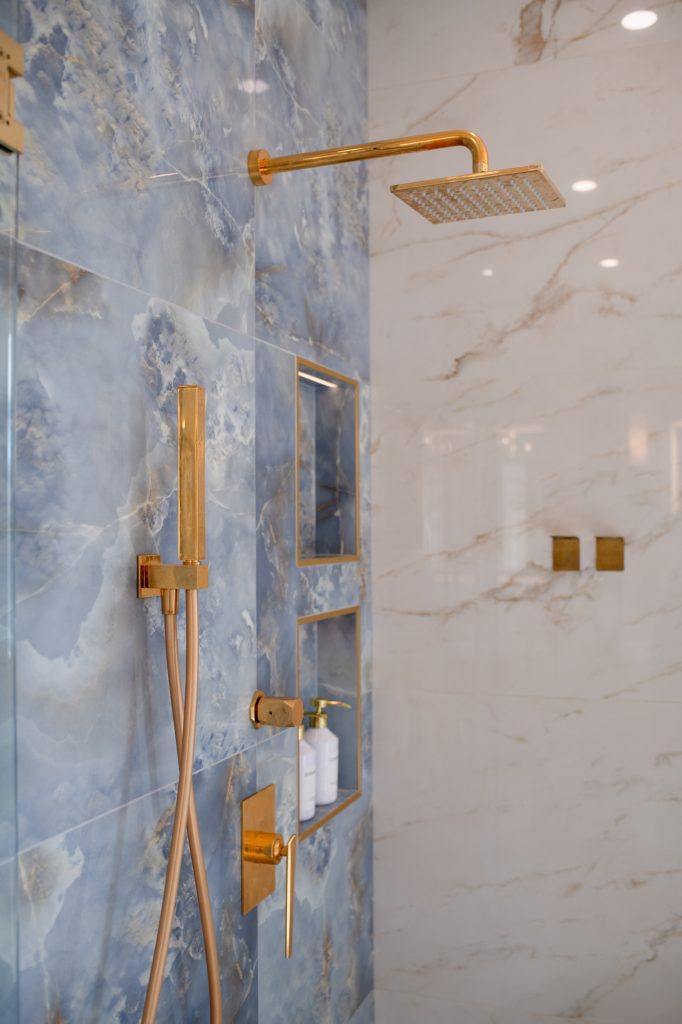 Luxury shower system with brass rain head, handheld wand, and valve trim on blue tile