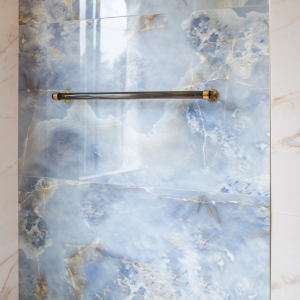 Towel bar mounted on a blue onyx-look tile wall with metallic end caps