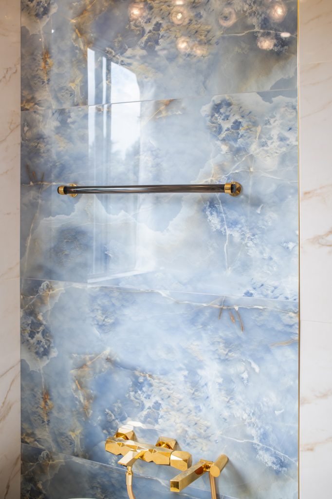 Towel bar mounted on a blue onyx-look tile wall with metallic end caps