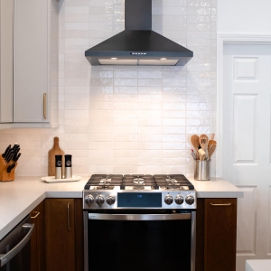 Gas range with black hood and white backsplash