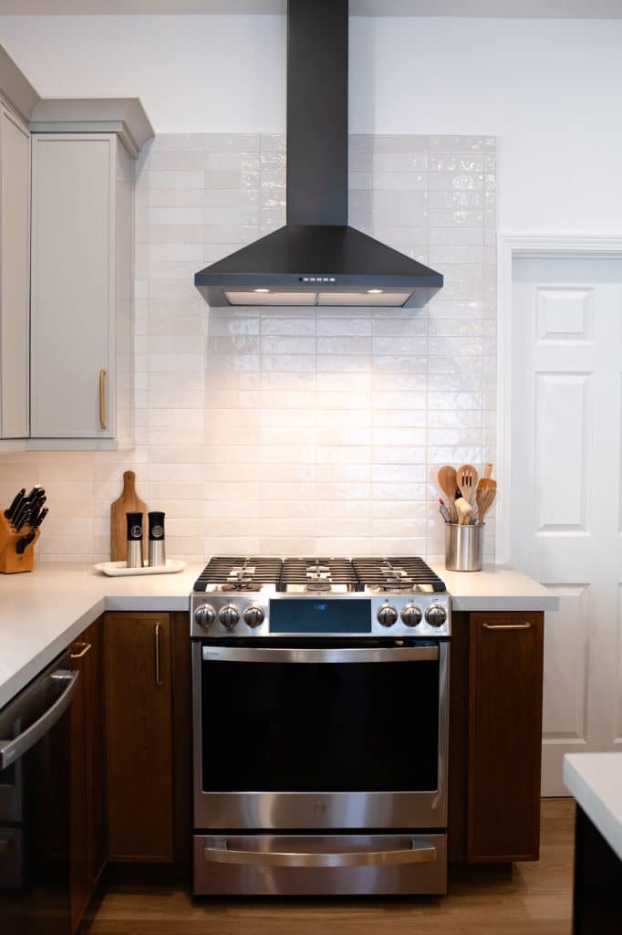 Gas range with black hood and white backsplash