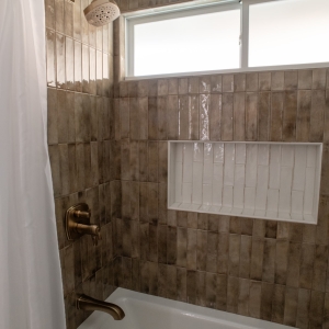 Close-up of bath shower with Delta fixtures and white tile niche