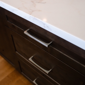 Stained knotty alder island with brushed hardware and white countertop