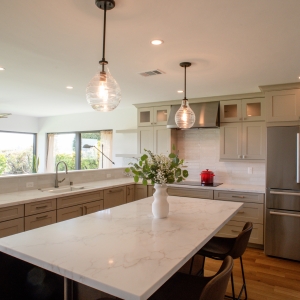 Kitchen island with Calacatta-style countertop, pendant lights, and custom cabinetry