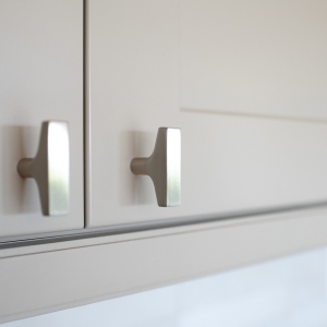 Close-up of brushed hardware on white upper kitchen cabinets