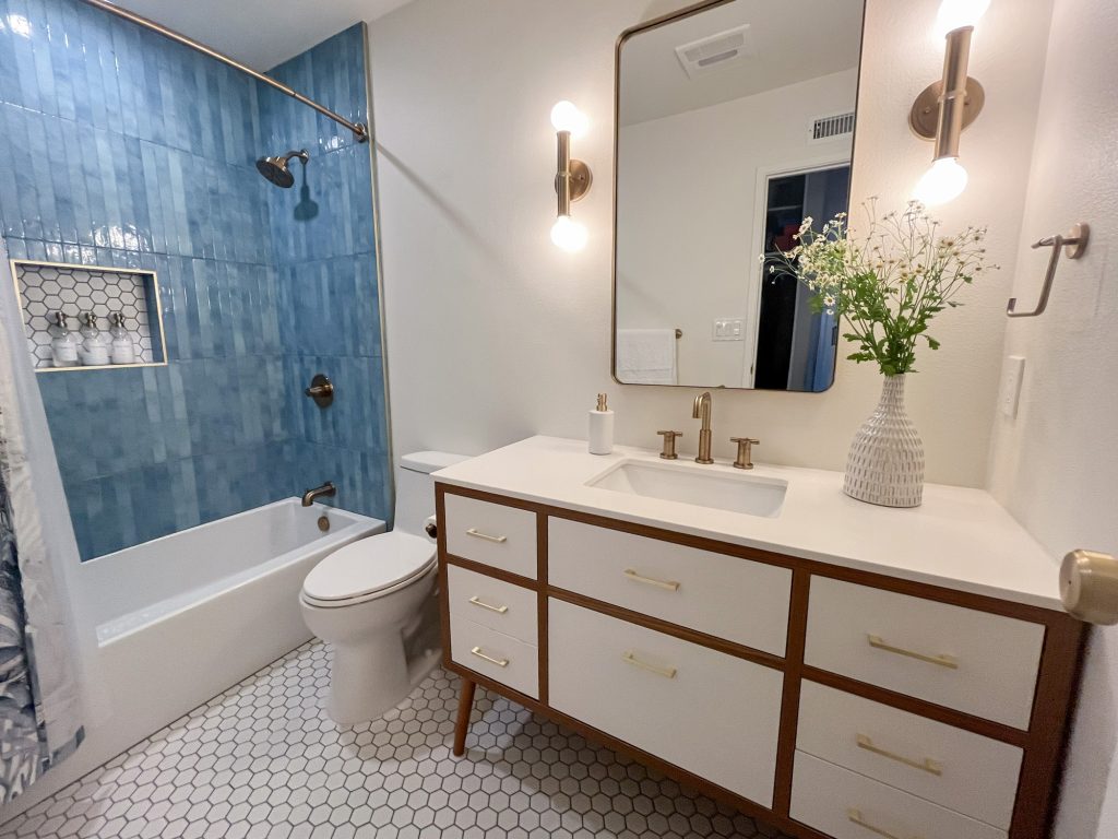 Hall bathroom with blue tile, white tub, and mid-century vanity