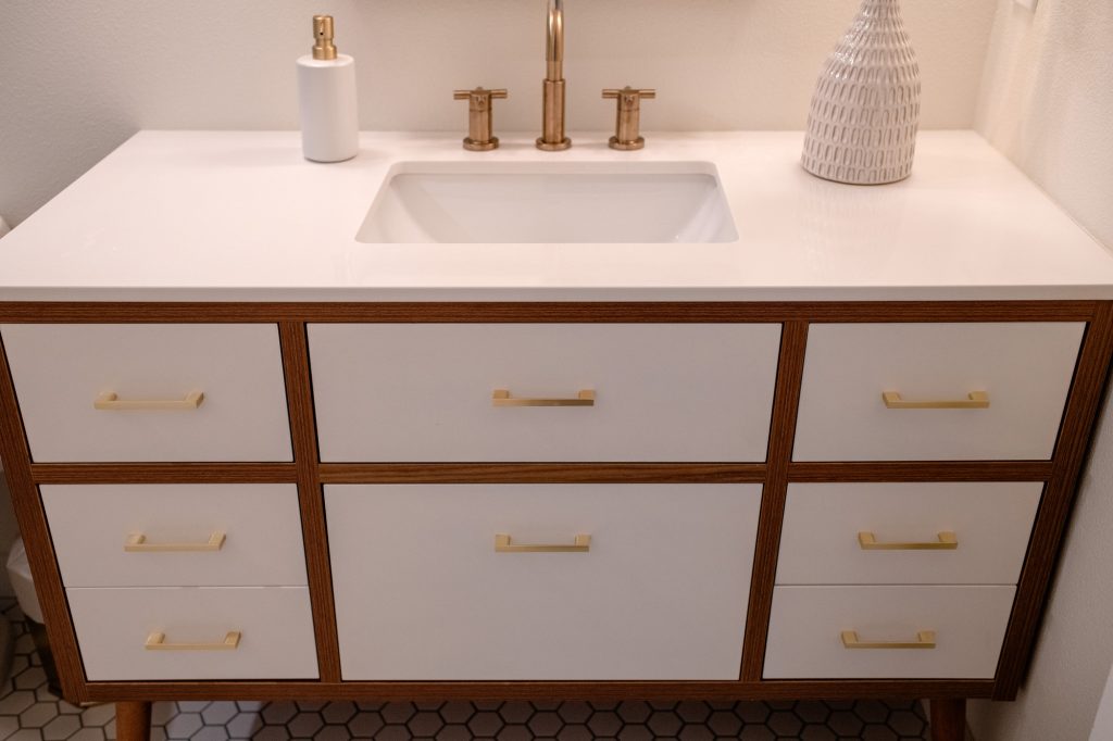 Hall bathroom vanity with white fronts and brass pulls
